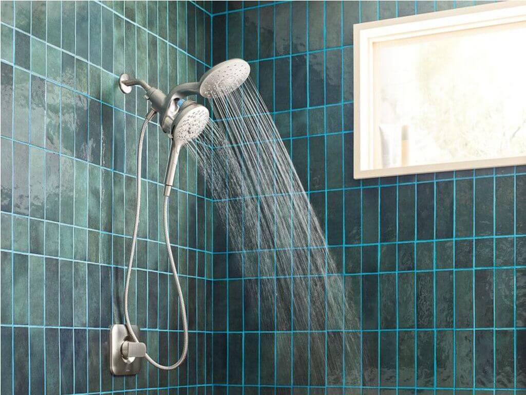 A shower head with a blue tiled wall behind it
