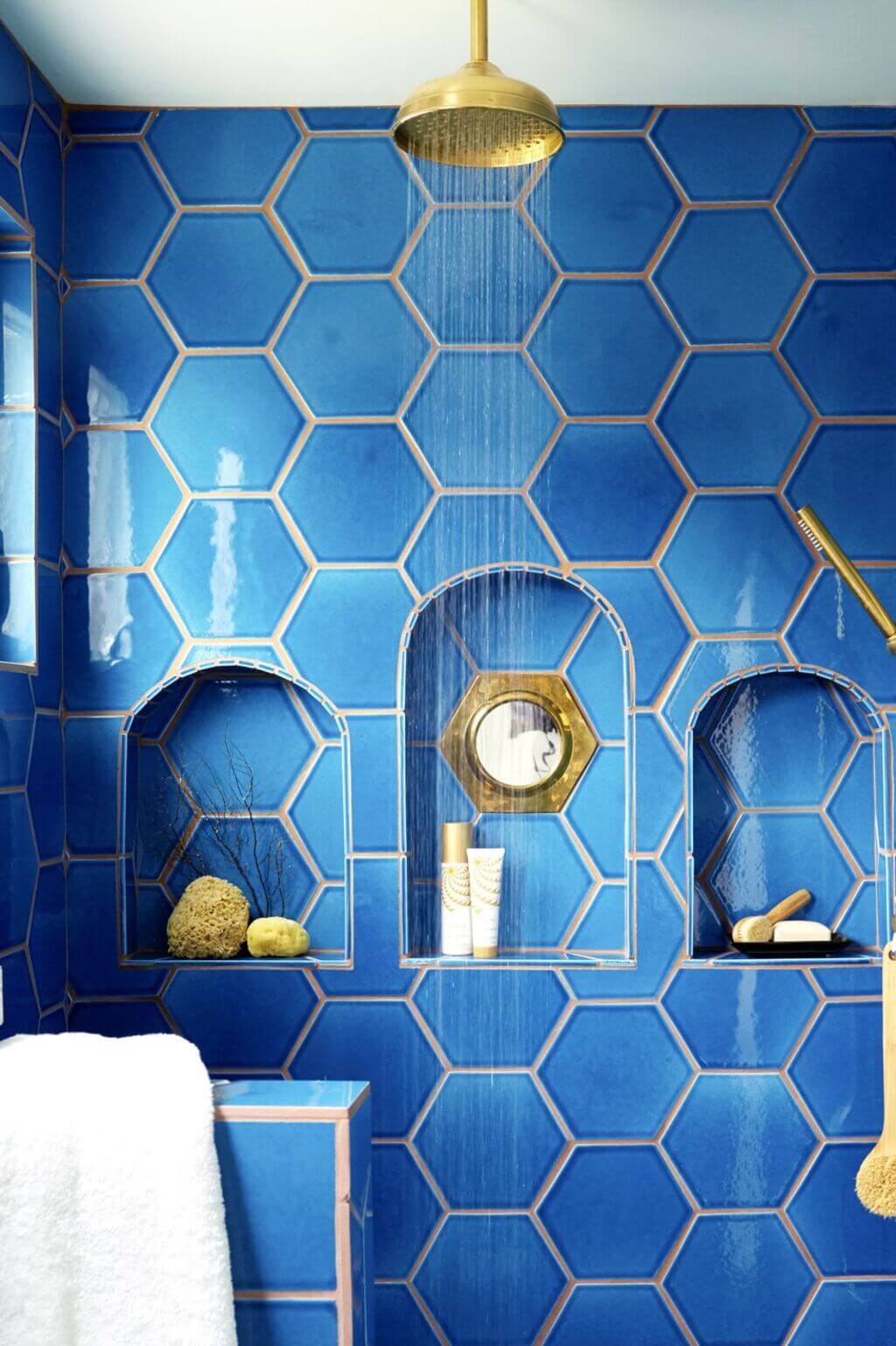 A bathroom with blue tiles and gold fixtures
