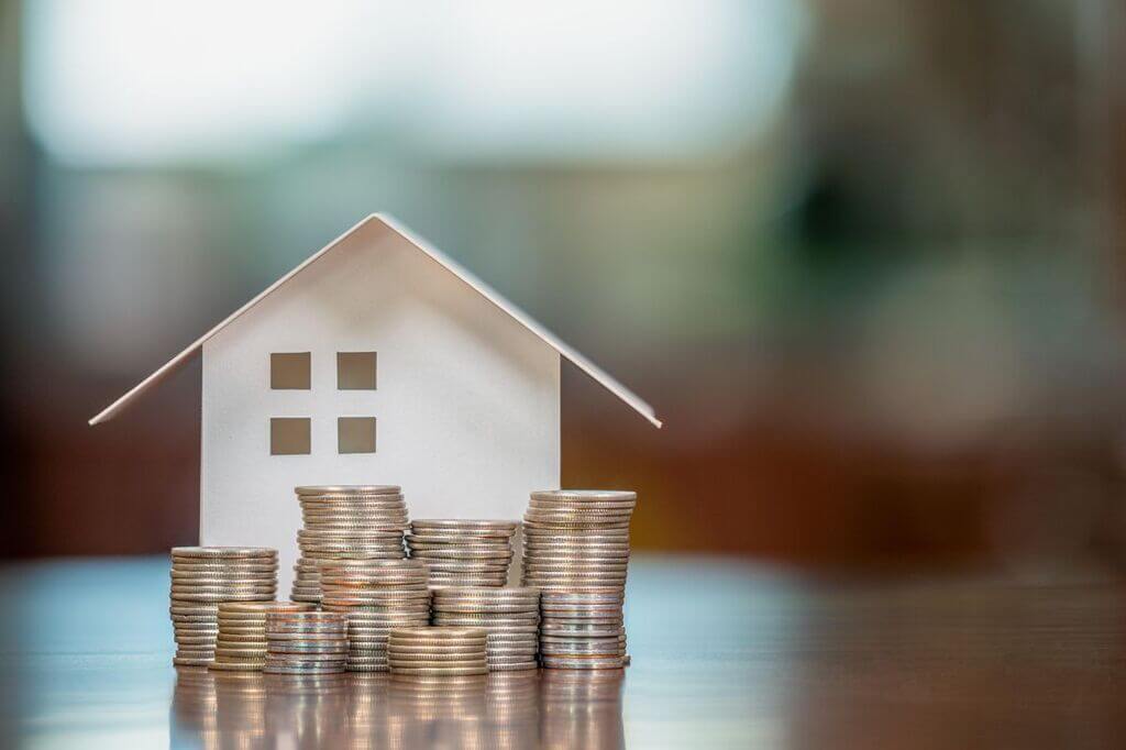 A small house sitting on top of a pile of coins
