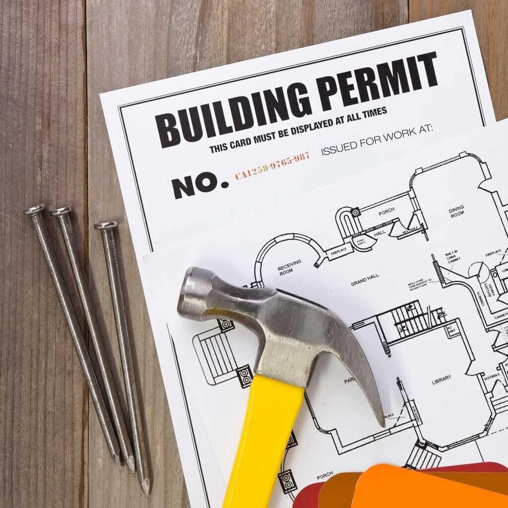A hammer and some screws on top of a building permit
