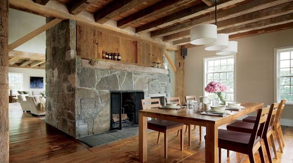 A dining room with a table and chairs and a stone fireplace
