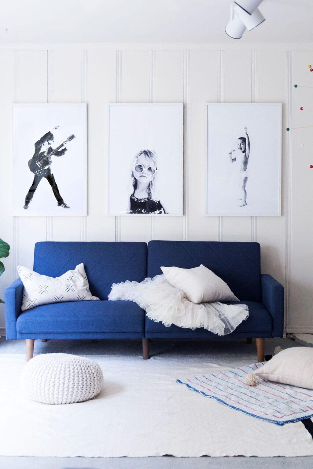 A living room with a blue couch and pictures on the wall
