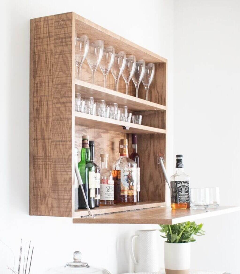 A wooden shelf filled with lots of bottles and glasses

