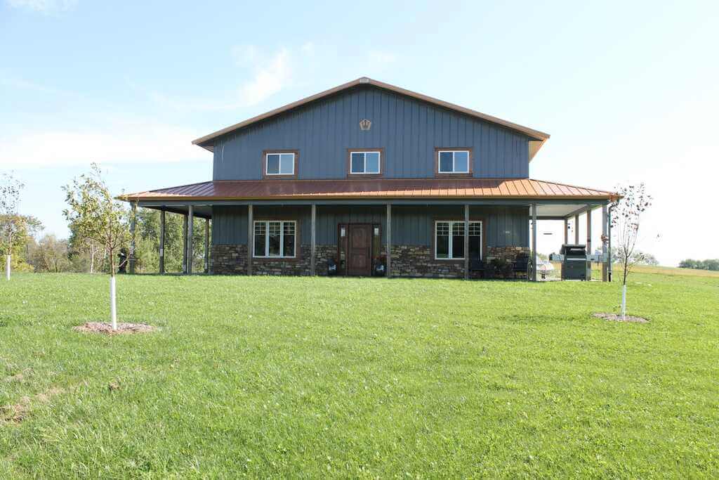 A large house with a metal roof in the middle of a field
