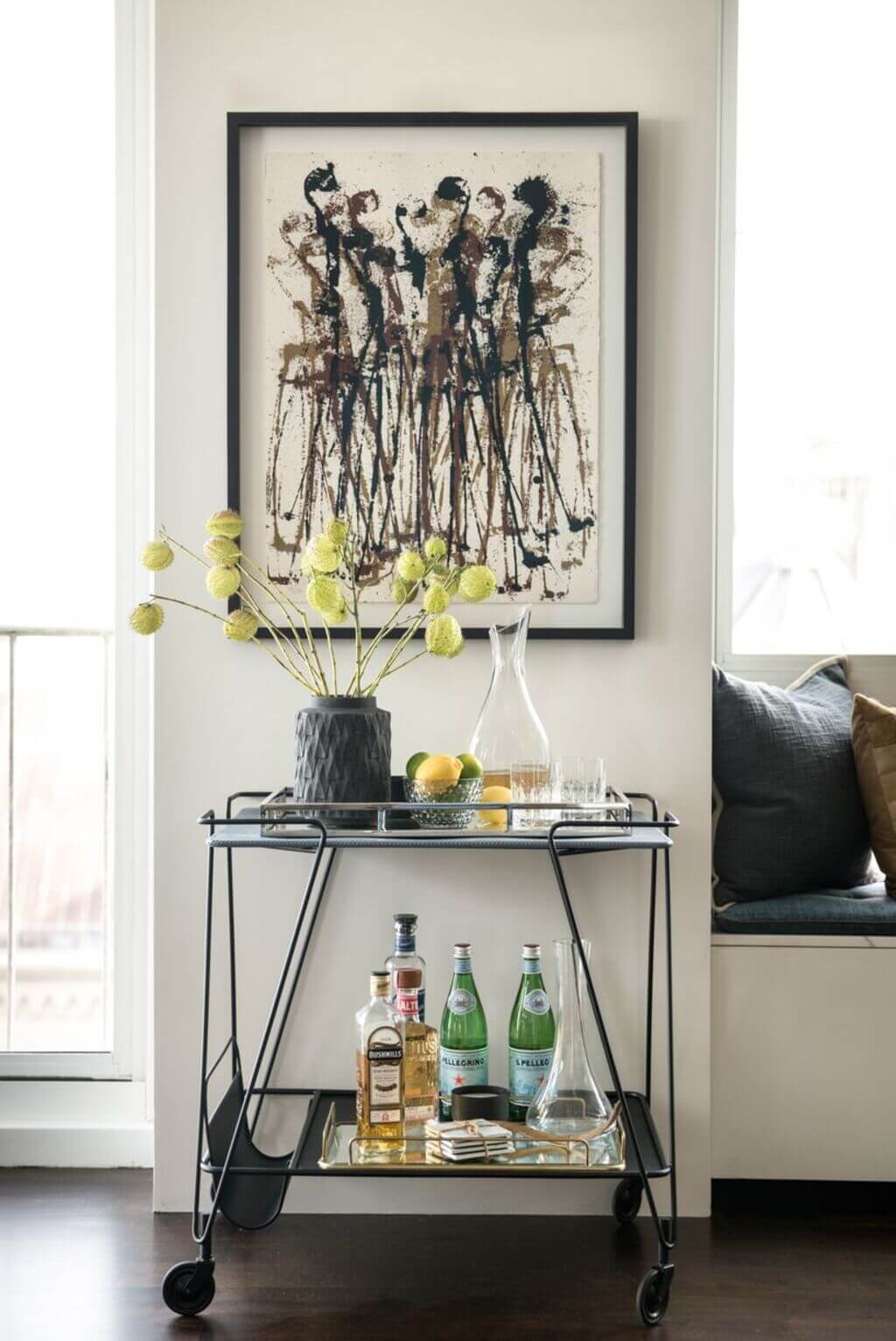A bar cart with bottles and glasses on it
