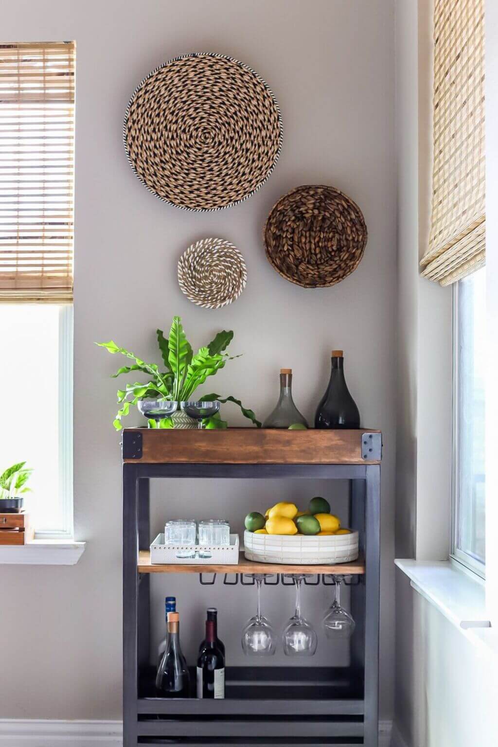 A bar cart with wine glasses, lemons, and a bottle of wine
