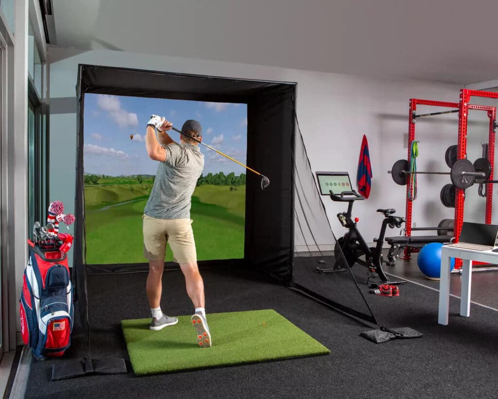 A man swinging a golf club in a golf simulator
