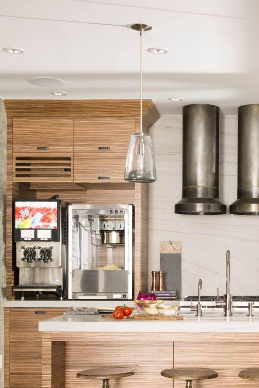 A kitchen with a stove, refrigerator, and stools
