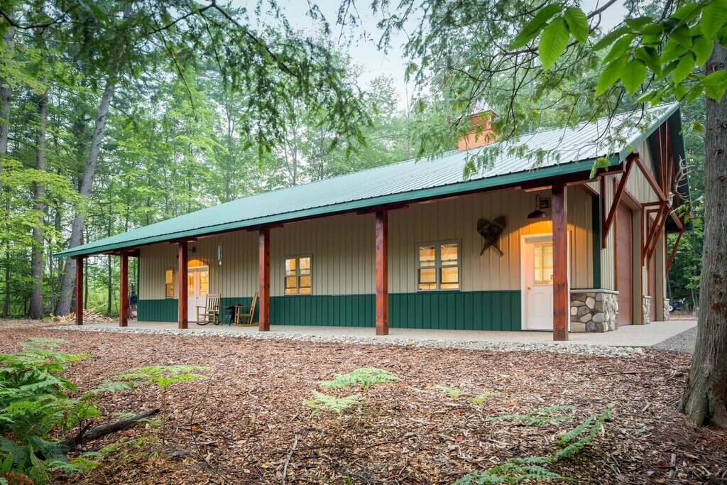 A small green and white cabin in the woods
