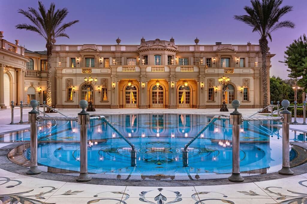 A large mansion with a pool in front of it
