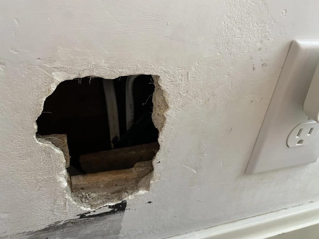 A hole in a wall with a light switch