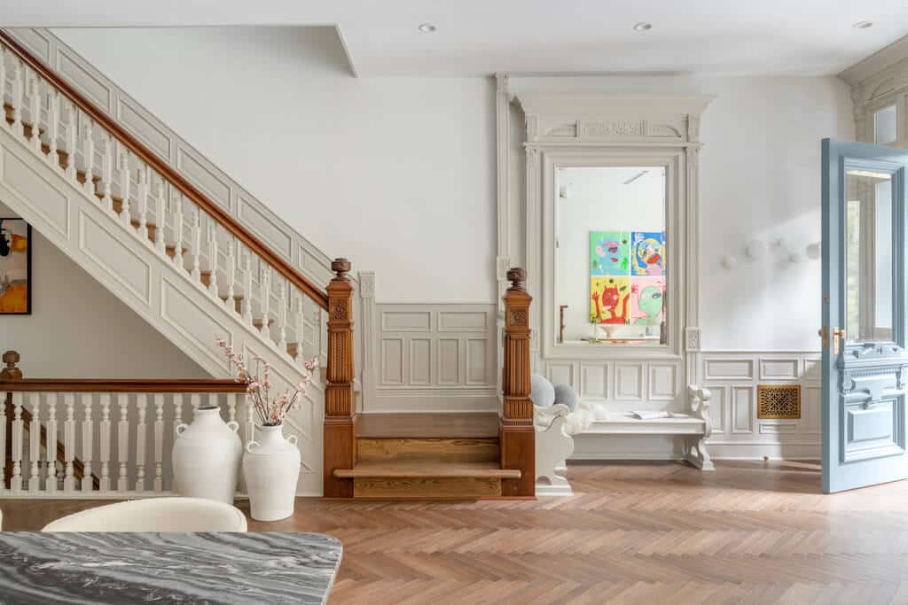 A living room with a staircase and a painting on the wall
