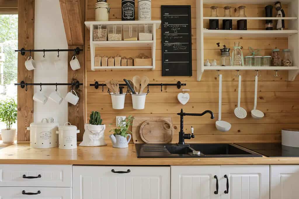A kitchen with wooden walls and white cabinets
