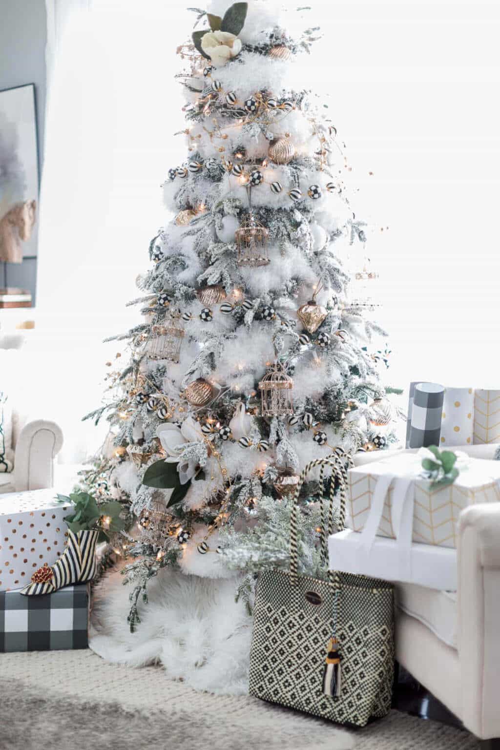 A white christmas tree in a living room with sofa 
