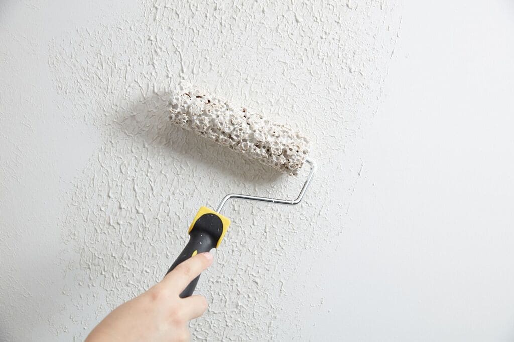 A person using a paint roller to paint a wall
