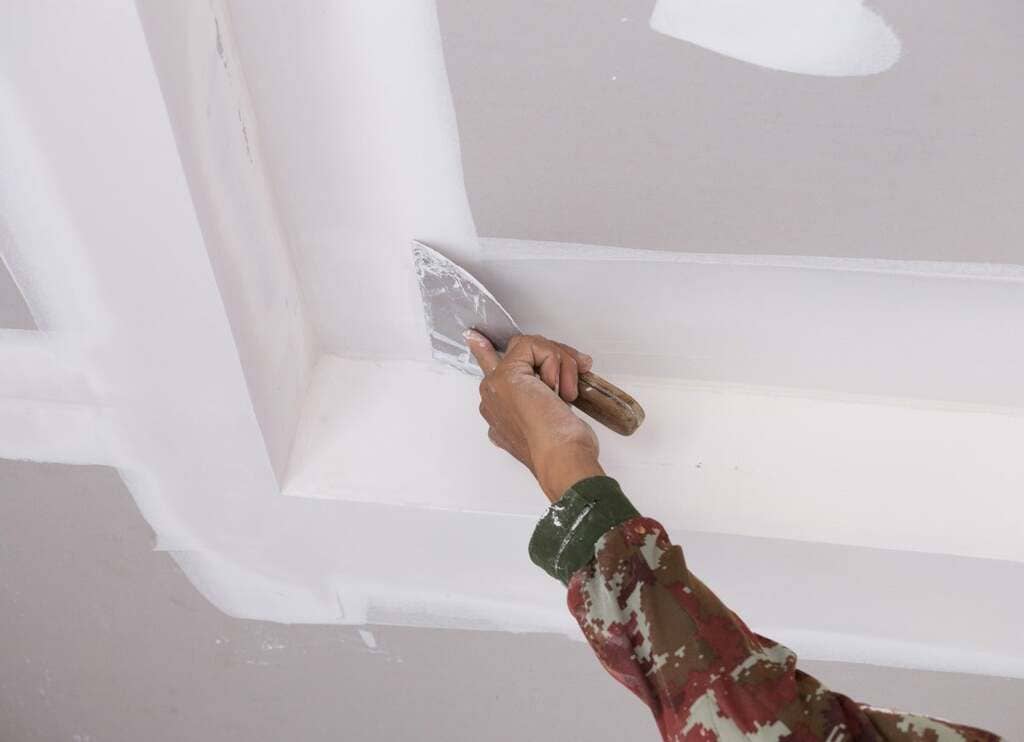 A person using a paint roller to paint a ceiling
