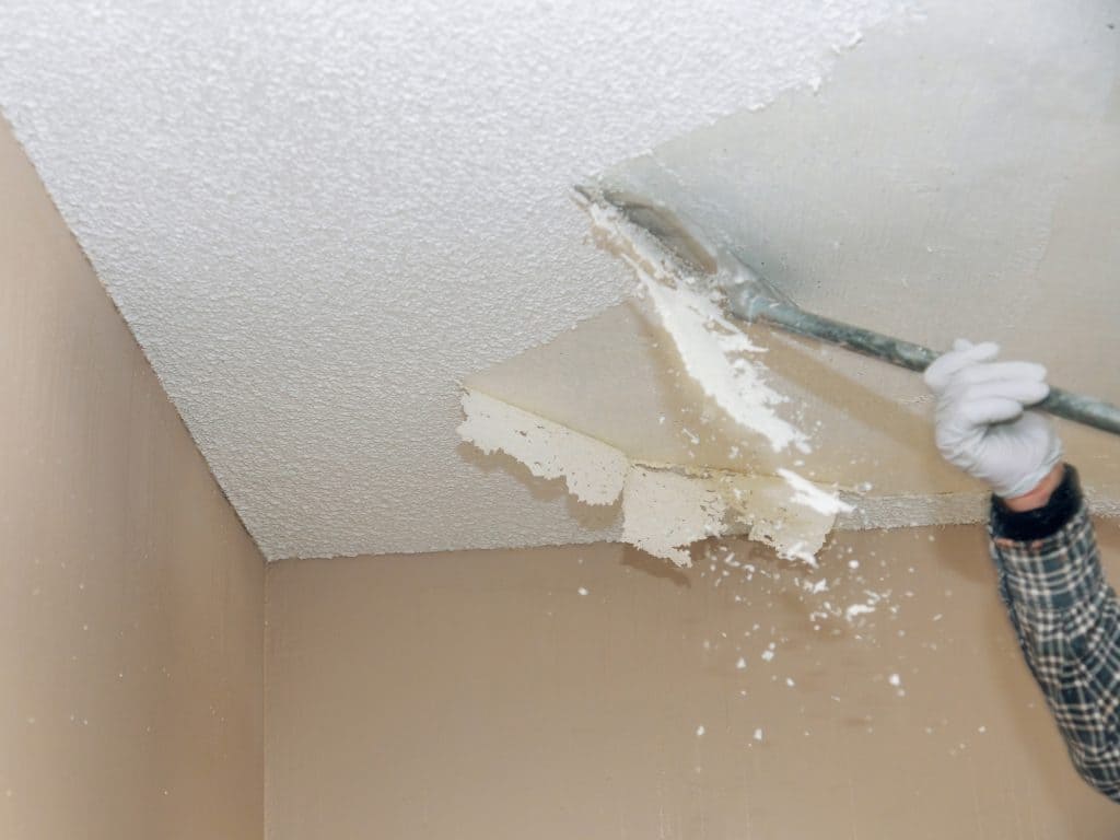 A man is painting a ceiling with a paint roller
