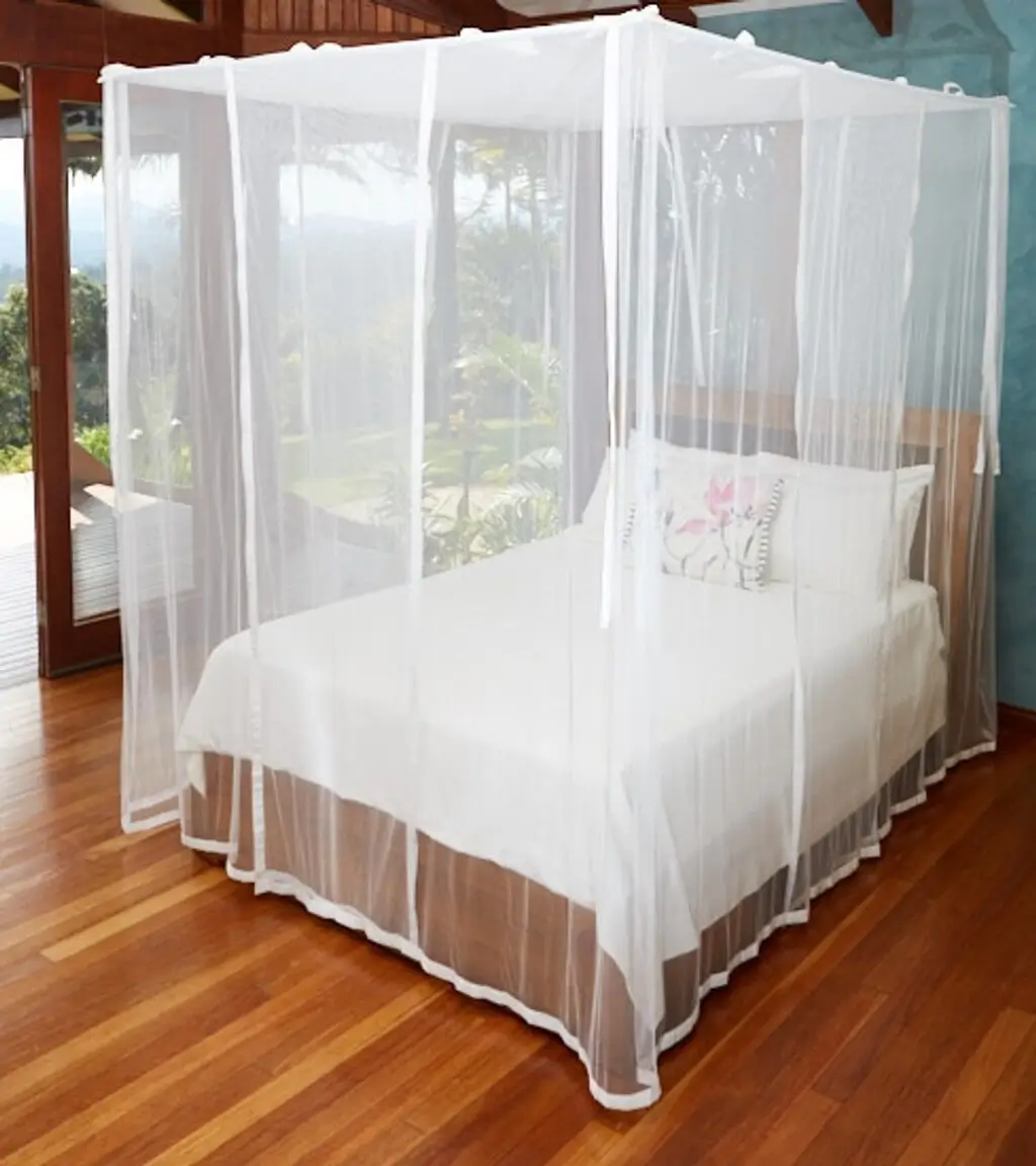 A bed with a white canopy over it on a wooden floor
