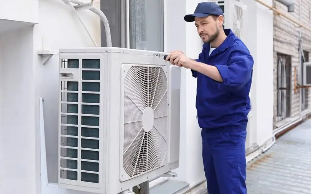 A man working on an air conditioner outside of a building
