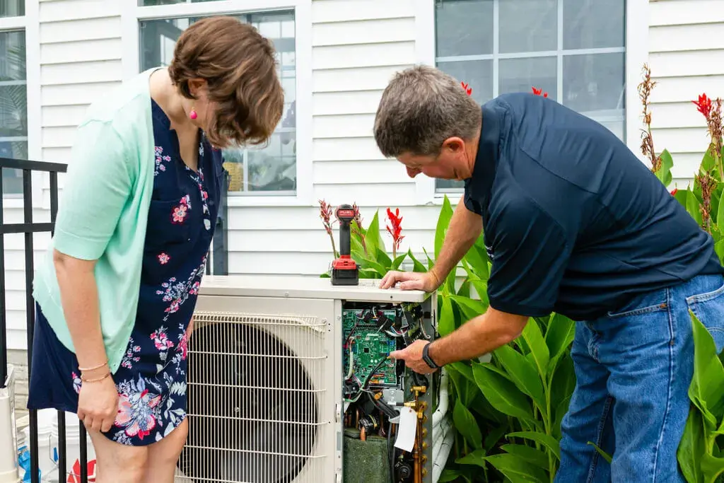 A man and a woman looking at an air conditioner
