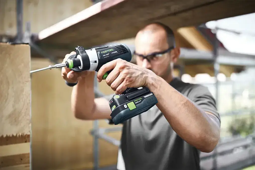 A man using a Cordless Drill to drill a piece of wood
