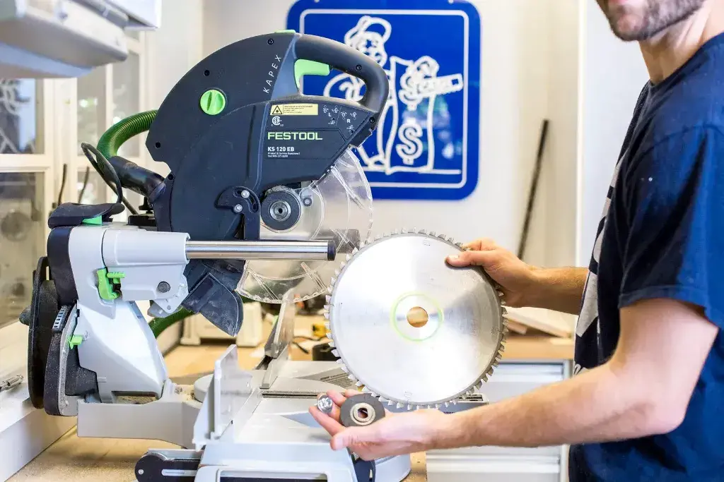 A man holding a Chop Saw in his hands