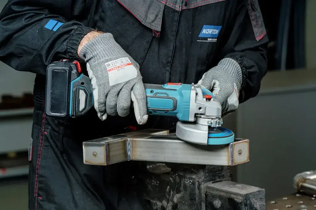 A person using a cordless  Grinder on a piece of metal
