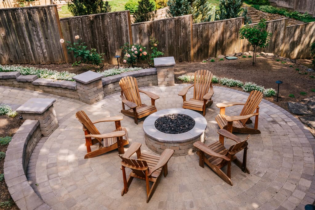 A fire pit with wooden chairs around it with retaining wall
