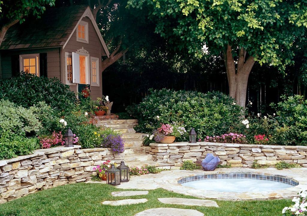 A garden with a hot tub surrounded by flowers and a retaining wall