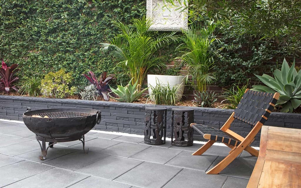 A patio with a grill and a retaining wall