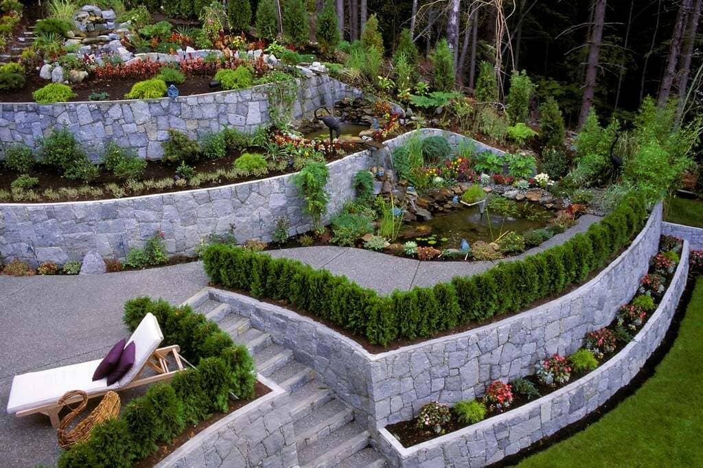 A garden with a stone wall and a retaining wall