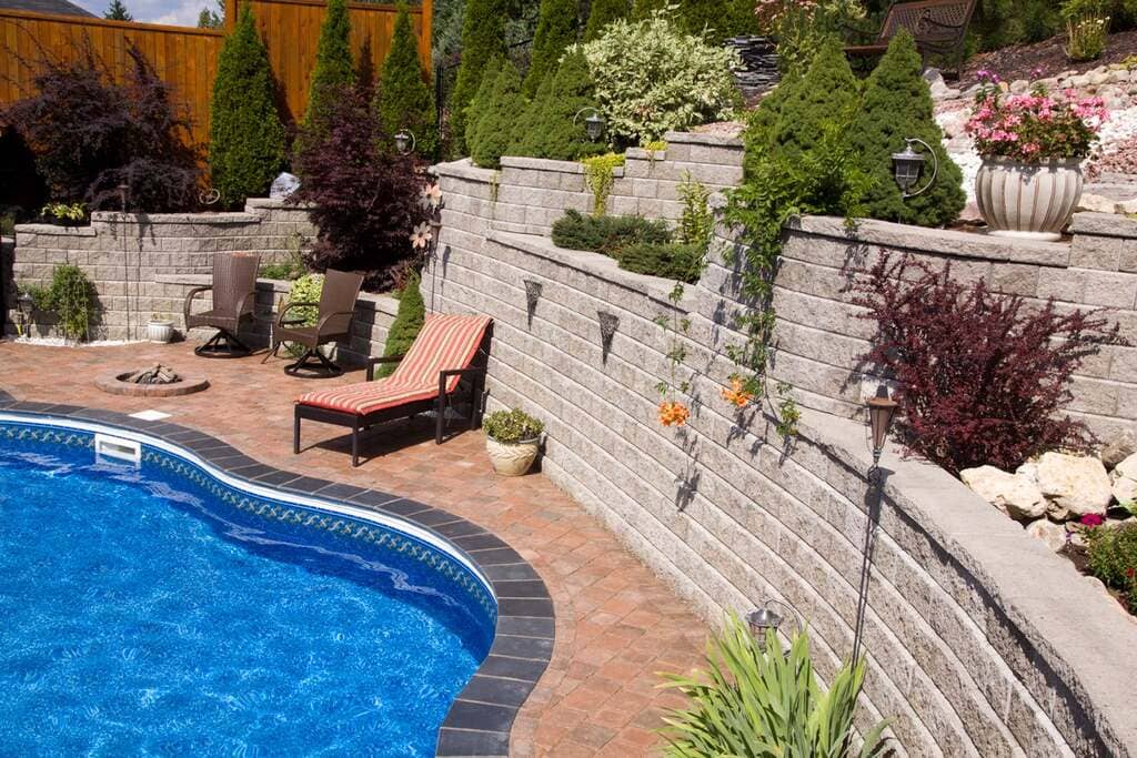 A backyard with a swimming pool and
 a retaining wall