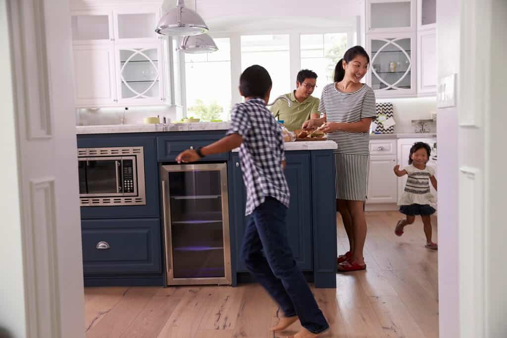 A group of people standing around a kitchen
