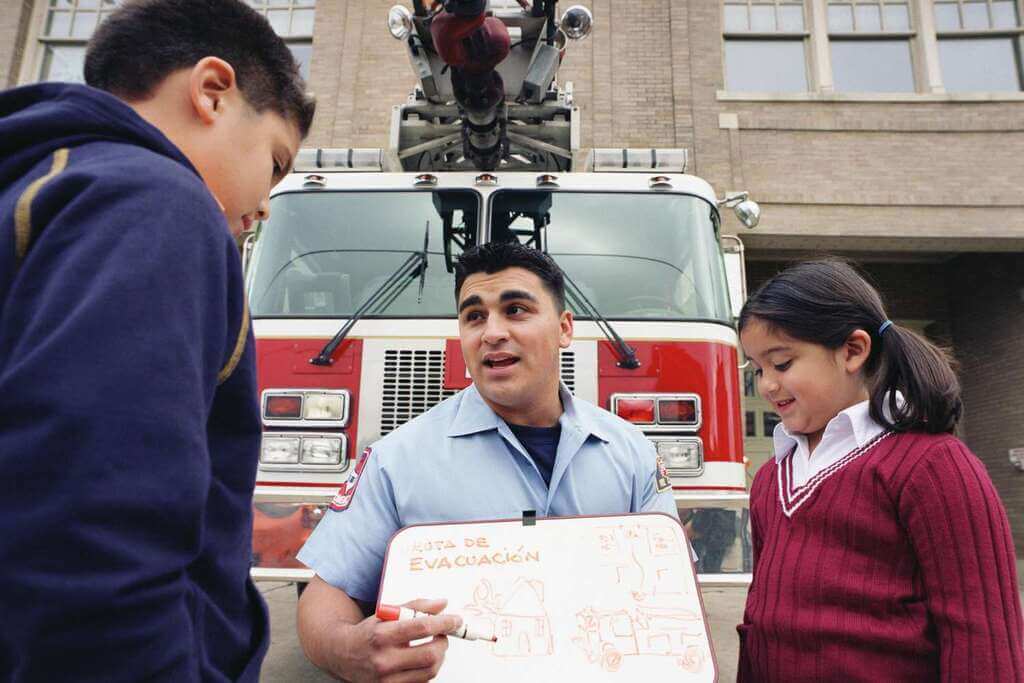A man standing next to a girl and a fire truck
