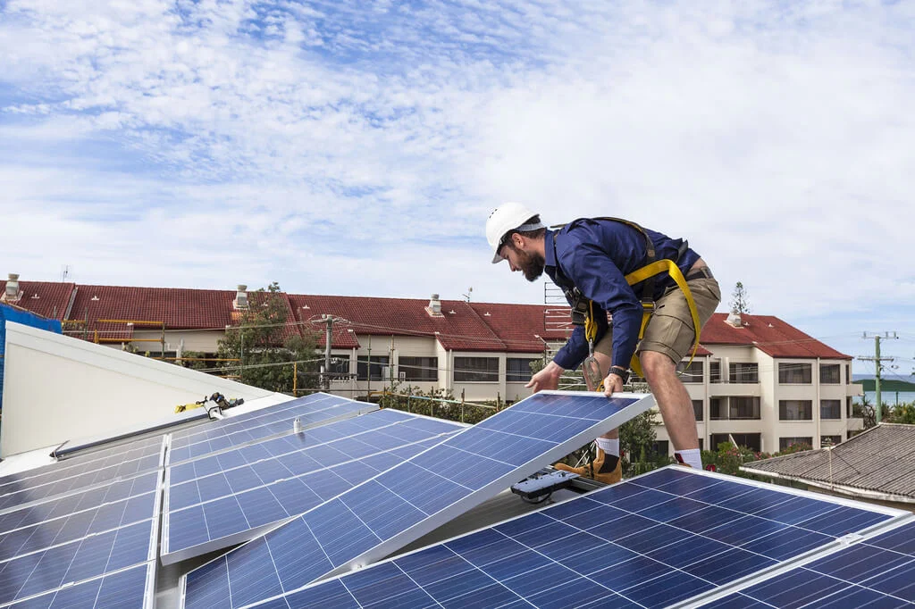 A man working on a solar panel on a roof
