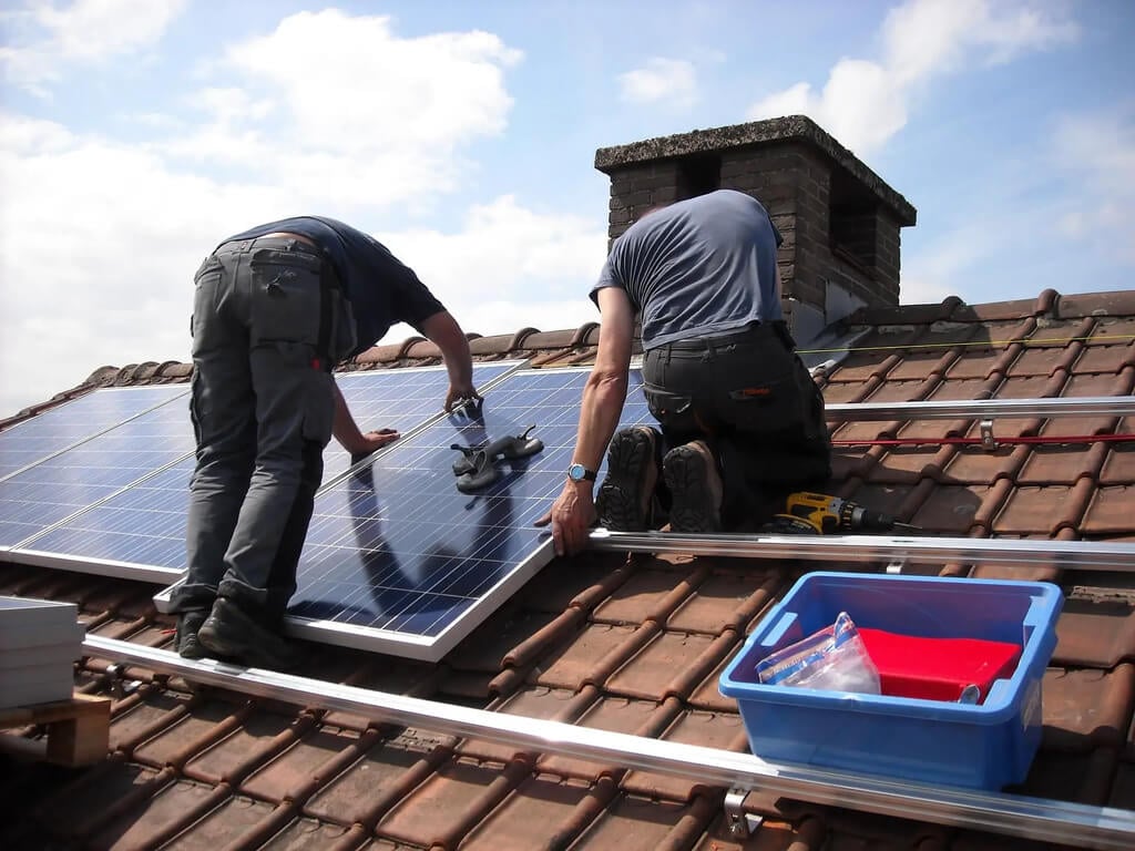 Two men working on a solar panel on a roof
