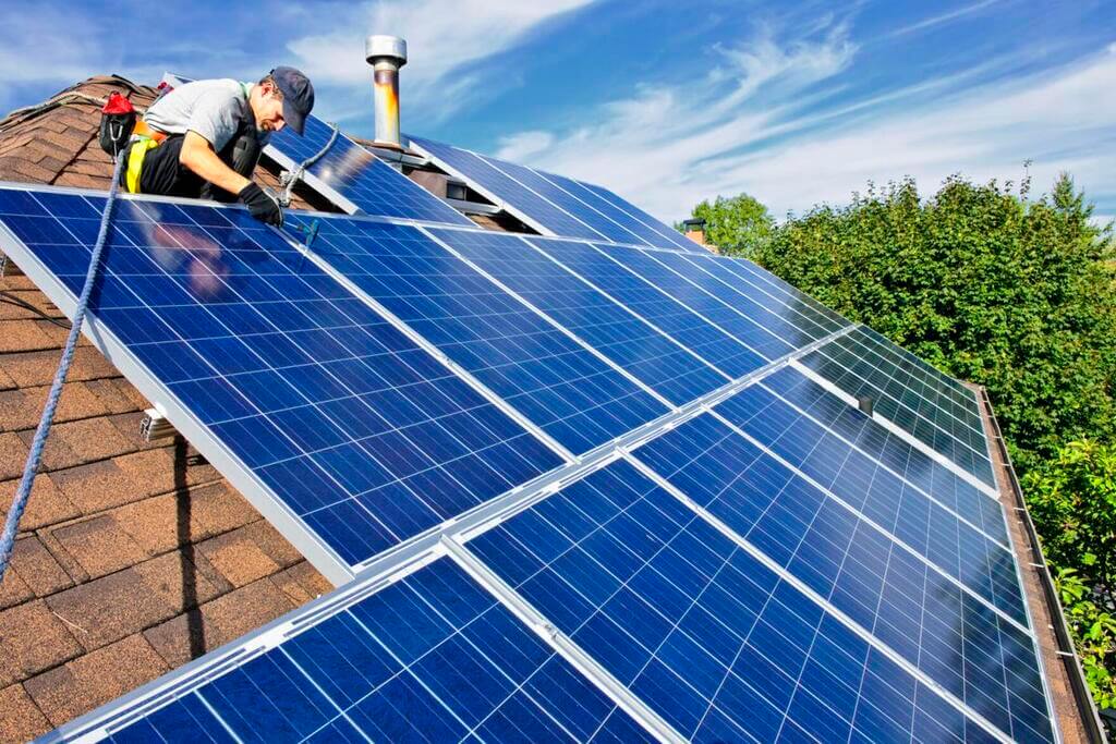 A man on a roof repairing a solar panel
