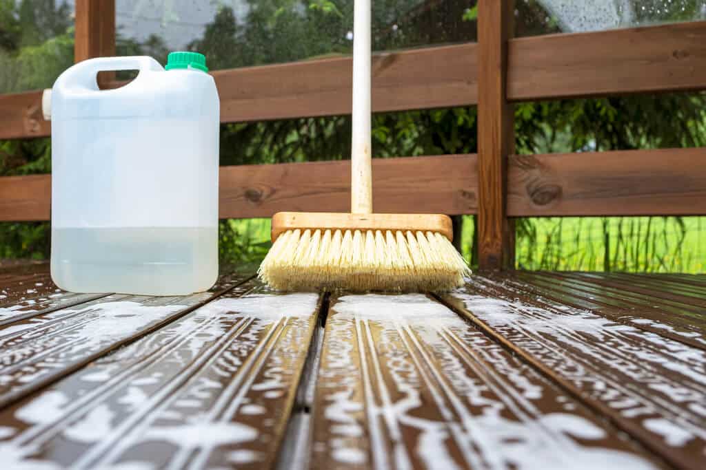 A broom and a bottle of cleaner sitting on a wooden table
