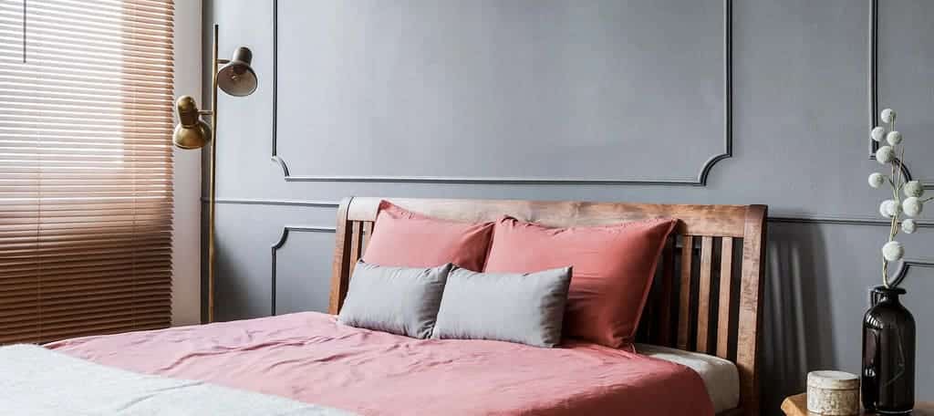 A bed with pink sheets and pillows in a bedroom
