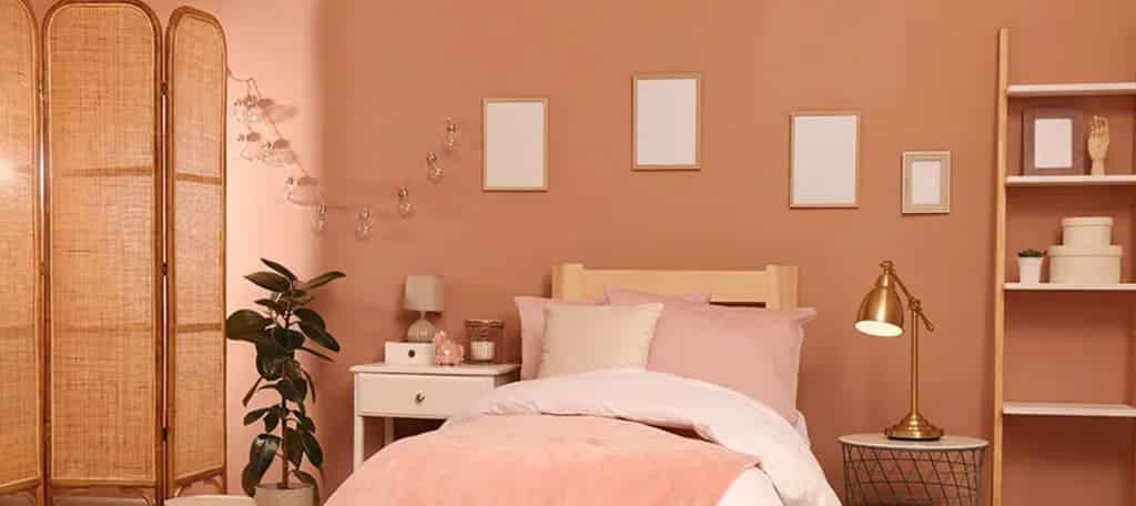 A bedroom with pink walls and a white bed
