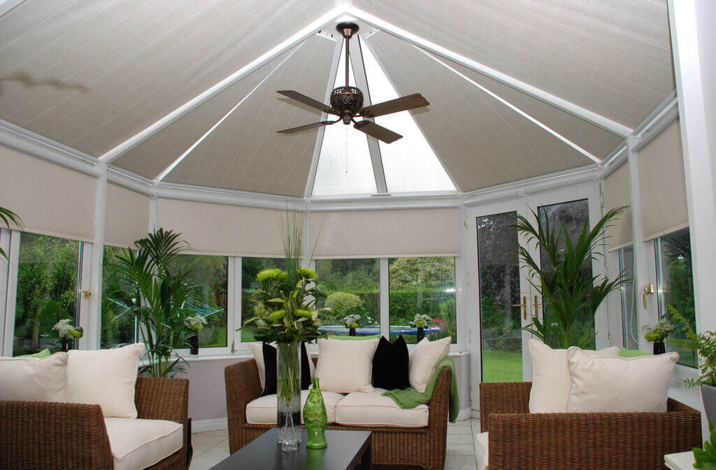 A conservatory with wicker furniture and a ceiling fan.