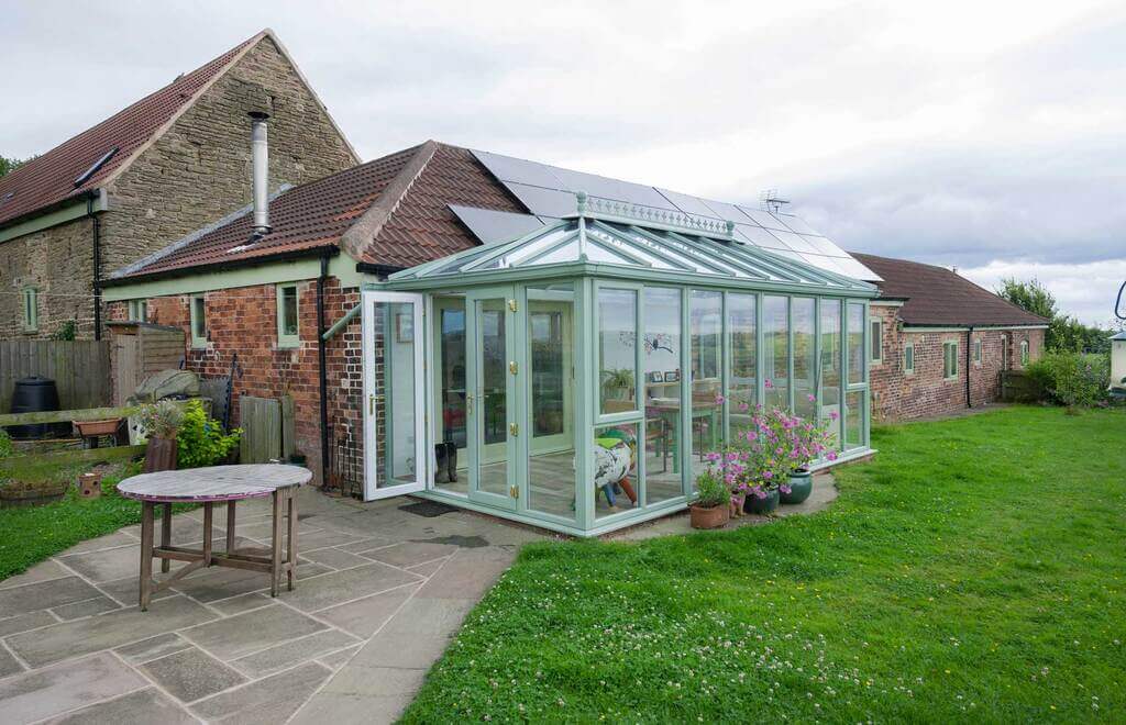 A house with a glass conservatory and solar panels.