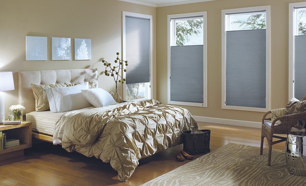 A bed sitting in a bedroom next to two window blinds
