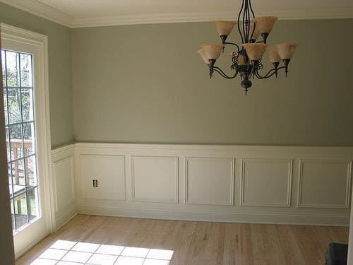 An empty room with a chandelier and hard wood floors
