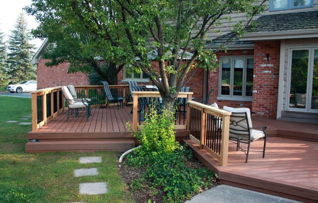 A wooden deck with chairs and a tree
