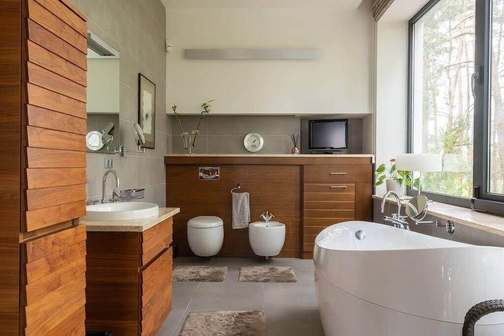 A bathroom with a tub, toilet, sink, and television
