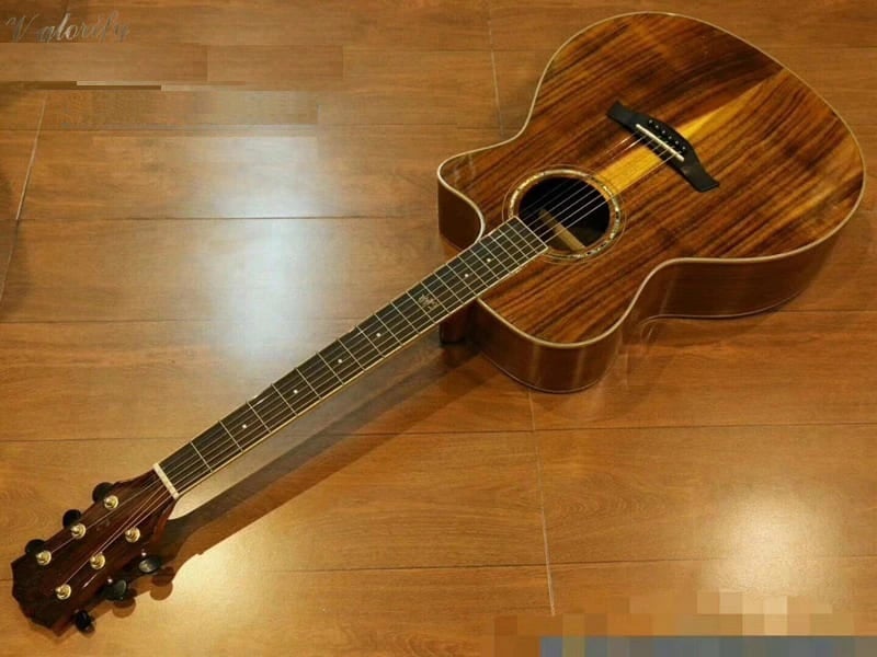 A wooden guitar laying on a hard wood floor
